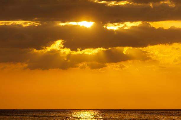 The sun is shining on the ocean. The sky is cloudy
