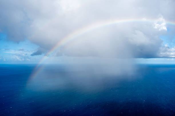 View from a balcony, looking out over the landscape to the Caribbean sea, with a rainbow arching over it.