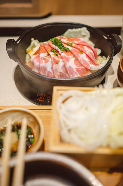 authentic asian hot pot dining experience, showcasing the communal style of cooking fresh ingredients like nabe and sukiyaki on a tabletop stove for a cozy family dinner.