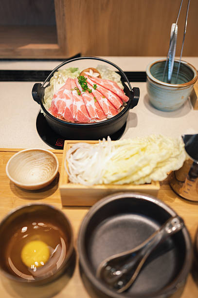 authentic asian hot pot steaming bowl of japanese shabu shabu featuring thinly sliced raw beef fresh tofu, and seasonal vegetables fresh ingredients like nabe and sukiyaki on a tabletop stove