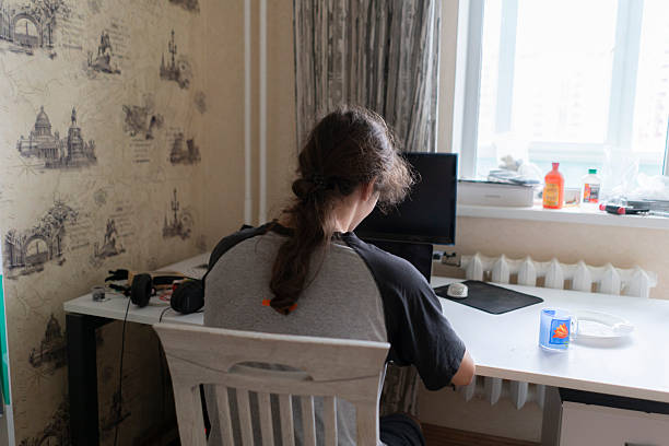 Person works at a desk in a room with a computer and basic supplies present.