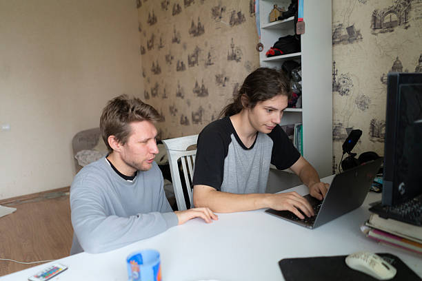 istock Two people sit at a desk working on a laptop while sharing ideas about a project 2255354035
