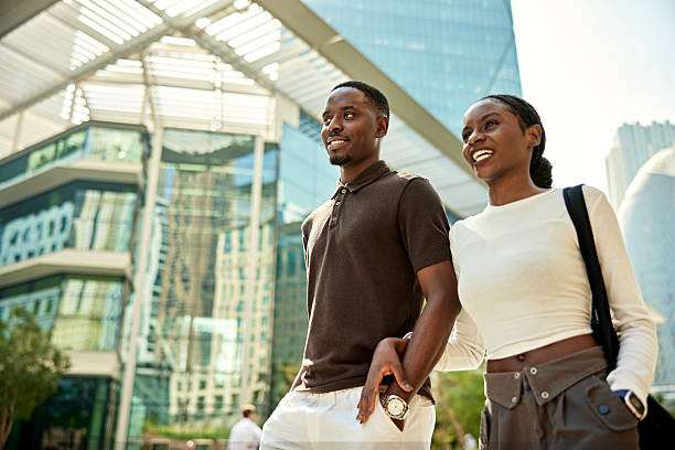 Three-quarter front view of young man and woman, casually dressed, arm in arm, taking a break from the office.