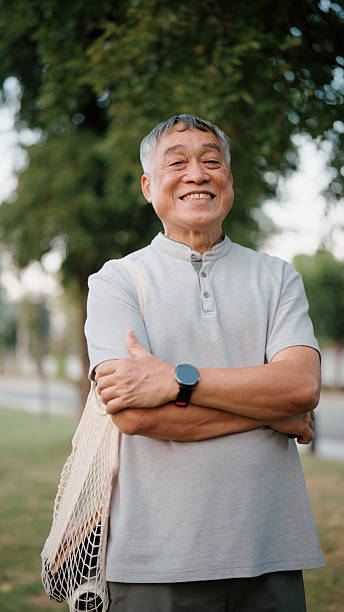 Smiling Asian senior man looking at the camera outdoors in a park