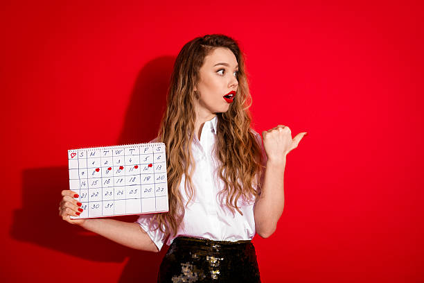 Blonde woman holding a calendar while gesturing. Stylish outfit on a red background. Perfect for concepts like planning, lifestyle, and fashion.