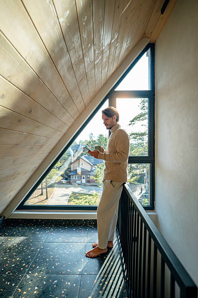 istock Man enjoying his coffee and using smartphone on a nice morning in a cozy mountain house 2255366885