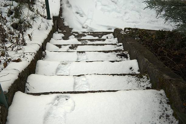 Snow covered stairs creating a slipping hazard in winter conditions. Visual warning concept about accidents, safety, and dangerous icy surfaces.