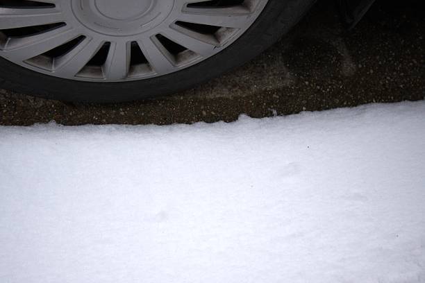 Car tire in snow shown in close-up view with Copy Space. Winter transportation and road safety concept highlighting driving conditions, traction, and seasonal travel risks.