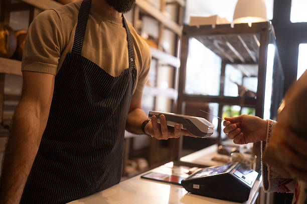 istock Unrecognizable bakery employee wearing an apron assists a customer with a contactless payment in a bread shop 2255370569