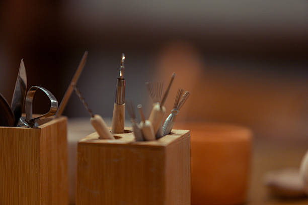 Close-up of a square wooden holder containing various pottery and sculpting tools