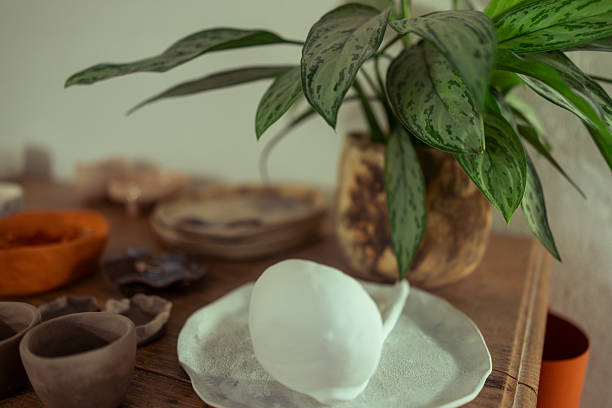 Minimalist White Ceramic Piece on Artisan Workbench with Studio Greenery