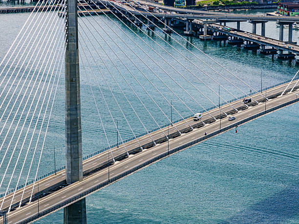 A cable-stayed bridge spans turquoise water at Cebu City port, Philippines. Cars traverse the roadway as ships and urban skyline create a dynamic harbor scene.
