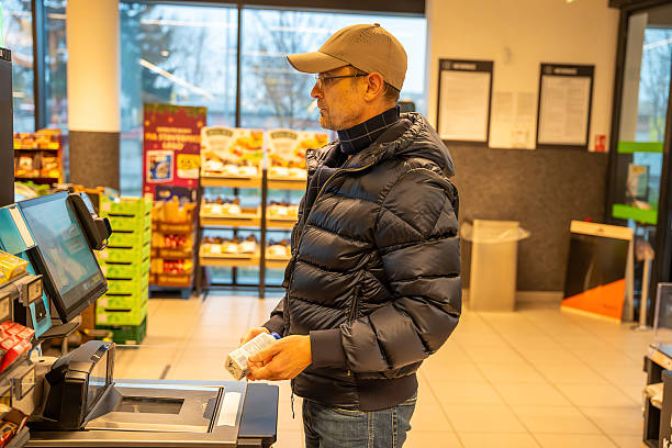 istock Man using a self-checkout machine at a grocery store, scanning items during a routine shopping trip. Concept of modern retail, automation, and independent shopping. 2255379730