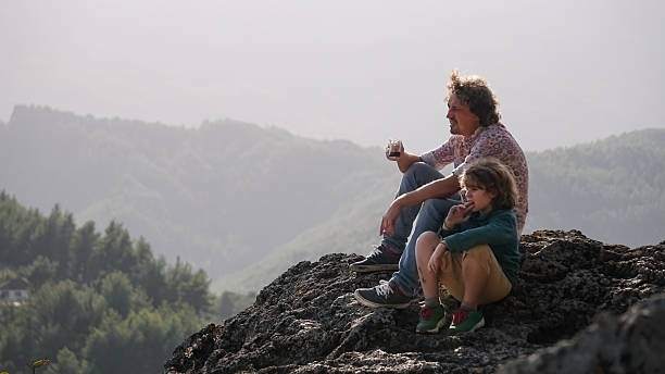 istock Father and teenage child on mountain ledge - sharing drinks with a view 2255380745