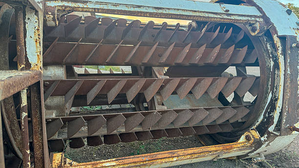 Large industrial rusted metal rotor with blades inside a weathered cylindrical housing.