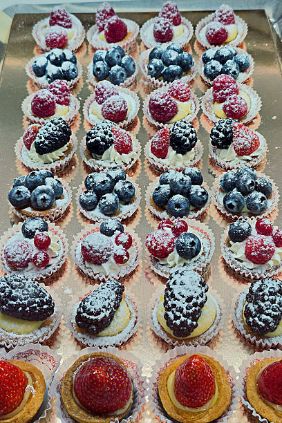 Assortment of fresh berry tarts dusted with powdered sugar, delightful dessert spread in window