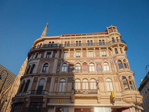 Vienna, Austria – Ground-level view of Michaelerplatz skyline, featuring St. Michael's Wing dome and Baroque rooftops with imperial eagles against the sky.