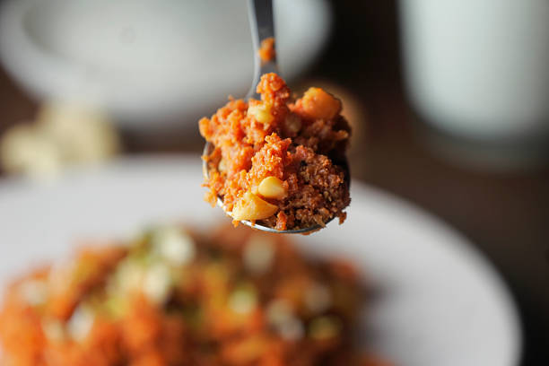 Detailed macro view of Gajar ka halwa on a spoon, showing its moist texture, vibrant color, and traditional nut garnish.