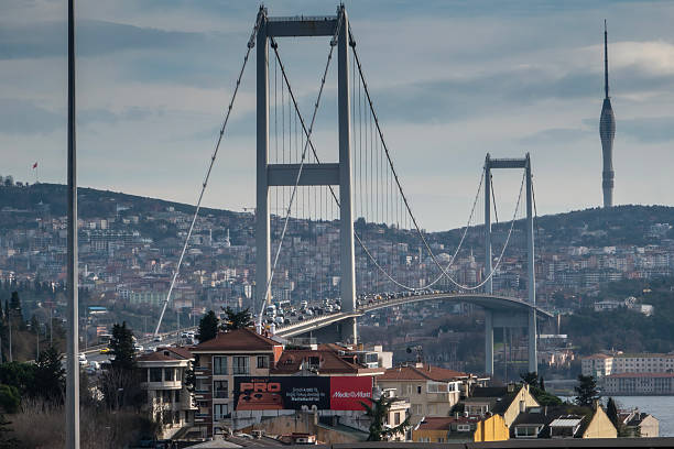 Istanbul, Turkey – January 5, 2026: Vehicles move along 15 July Martyrs Bridge (Bosphorus Bridge), with the city skyline and a communication tower visible on the hills in the background, reflecting daily urban traffic in İstanbul.