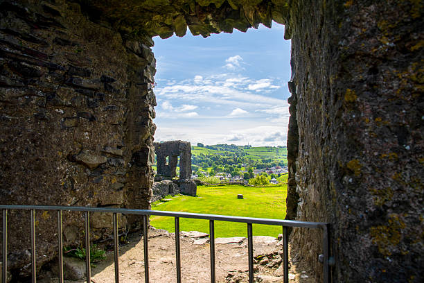 The medieval ruins of Kendal Castle overlooking green countryside in Cumbria, England, under a bright blue sky in the Lake District National Park.