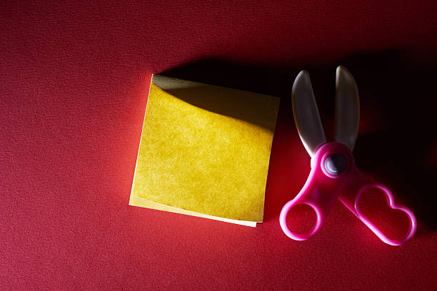 toy plastic sicssors and blank note pad on red background
