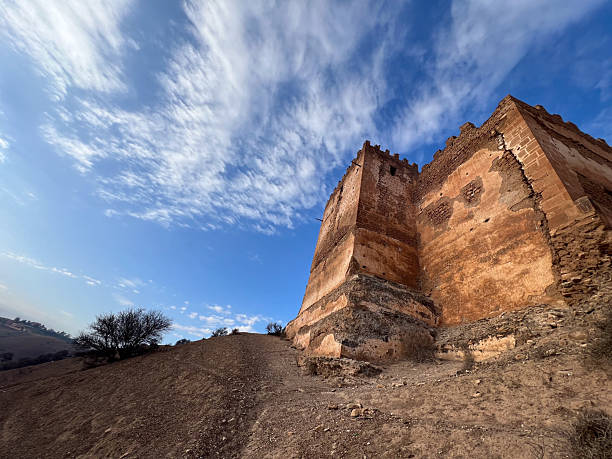 A low-angle view of the wall and a tower of the Boulaouane Kasbah.