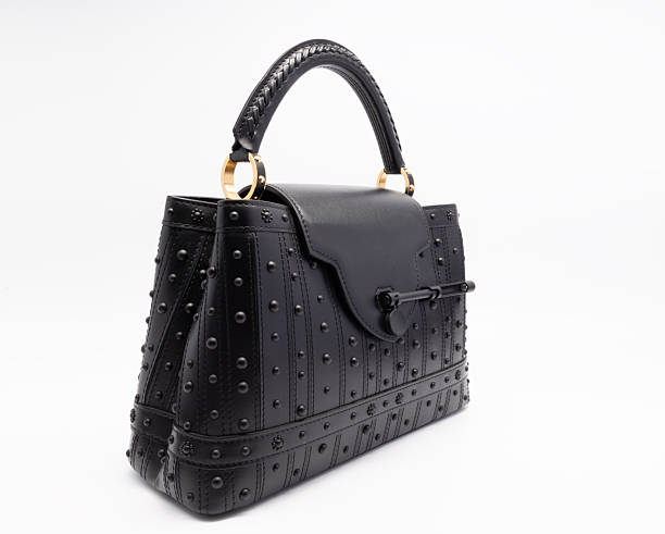 A studio shot of a luxury black leather top handle handbag featuring studded textured surface, structured silhouette, braided handle detail, gold metal rings, and secure clasp closure, presented from front, side, and angled views, isolated on a clean white background with copy space, suitable for fashion catalog, e-commerce, luxury accessories, and premium product presentation