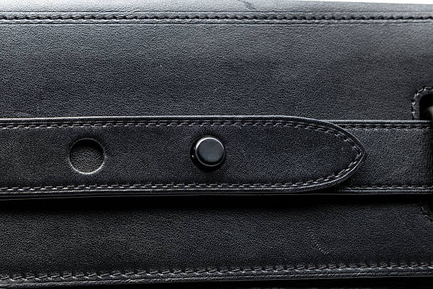 A studio close-up of a luxury black leather handbag highlighting studded textured surface, smooth leather flap, secure metal bar clasp closure, and fine stitching details, photographed as macro product details, isolated on a clean white background with copy space, suitable for fashion catalog, e-commerce, luxury accessories, and premium craftsmanship concepts