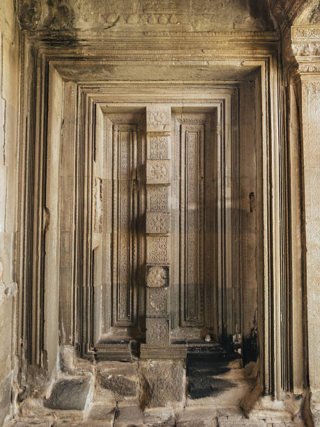 Angkor Wat stone doorway interior with layered Khmer mouldings and ornate sandstone carvings, captured in soft temple light. Concept, high quality image for travel guides and heritage media.