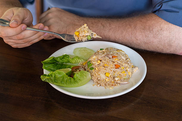Man Eating Fried Rice with Fork at Table. Thai food