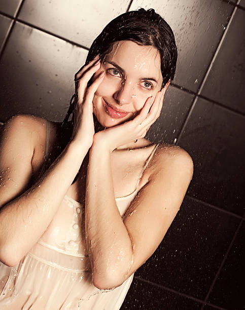Smiling young woman taking a morning shower in the modern bathroom.