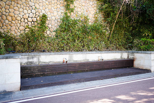 The resting bench under the stone wall and bamboo shadows