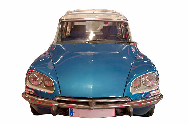 A classic car stands parked indoors, highlighting its blue exterior. The front view shows the headlights and grill design. It captures the essence of vintage auto design with clear lines.