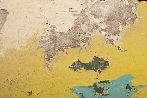 This image showcases a distressed surface with layers of faded yellow and beige hues, revealing underlying textures and imperfections perfect for adding character to any project