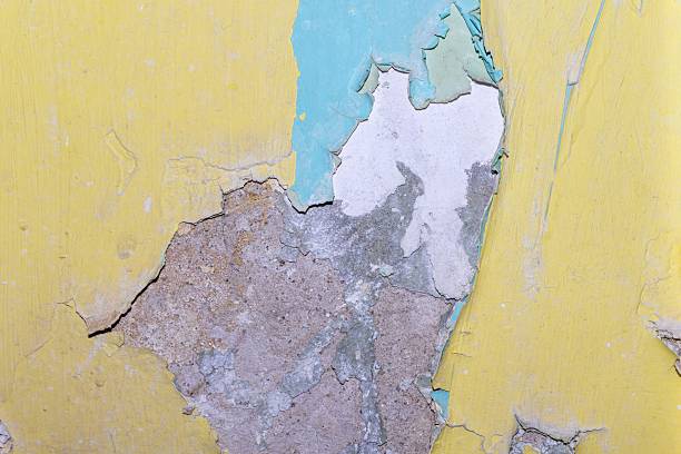 This image showcases the decaying surface of an old painted structure exhibiting peeling layers and visible damage