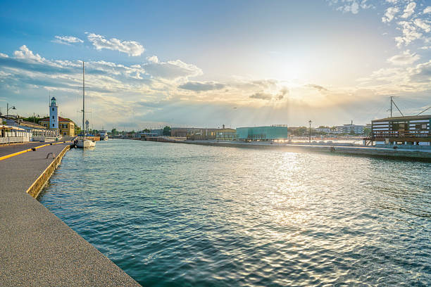 View of the Porto Canale Leonardesco in Cesenatico at sunset. The lighthouse and traditional fishing huts under a sunset sky in Emilia-Romagna, Italy