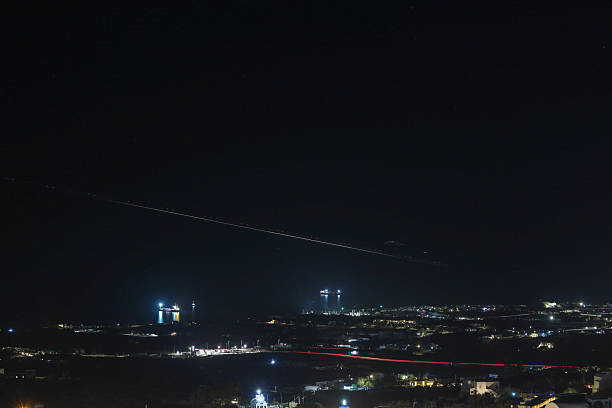 nighttime view over Santorini, capturing an aircraft's light trail
