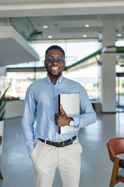 istock Smiling businessman holding laptop standing in modern office 2255411355
