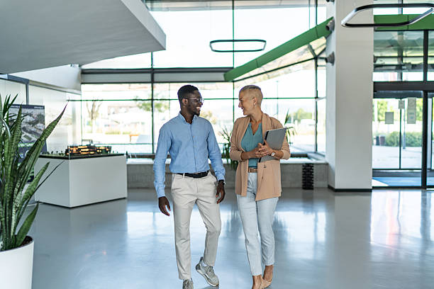 istock Business colleagues walking and communicating in office lobby 2255411997