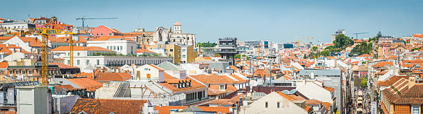Panoramic blue skies above the terracotta rooftops and crowded streets of the Baixa shopping district in the heart of Lisbon, Portugal’s vibrant capital city.