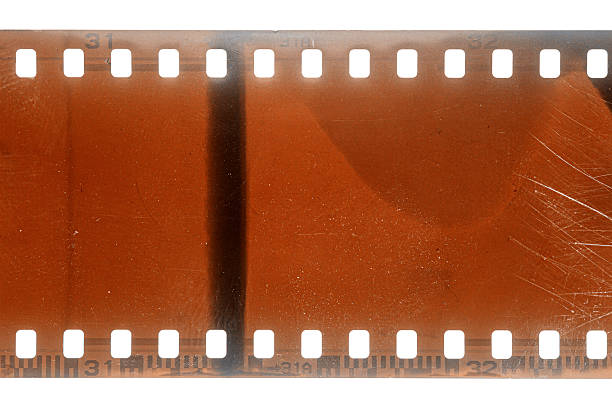 Dusty and grungy 35mm film texture or surface. Perforated scratched camera film isolated on white background.