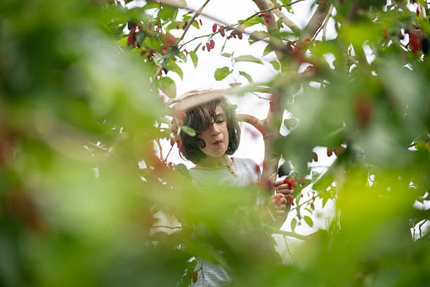 Rear view of a beautiful, young woman in red dress enjoying among trees in bloom.