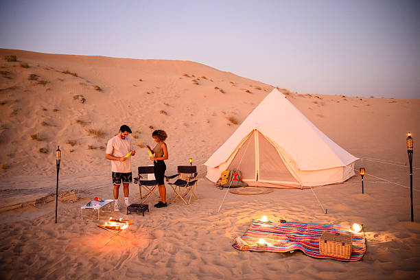 istock Couple glamping in desert at sunset preparing dinner 2255429418