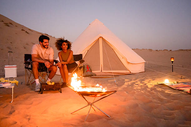 istock Couple camping in desert sitting by campfire at sunset 2255429469