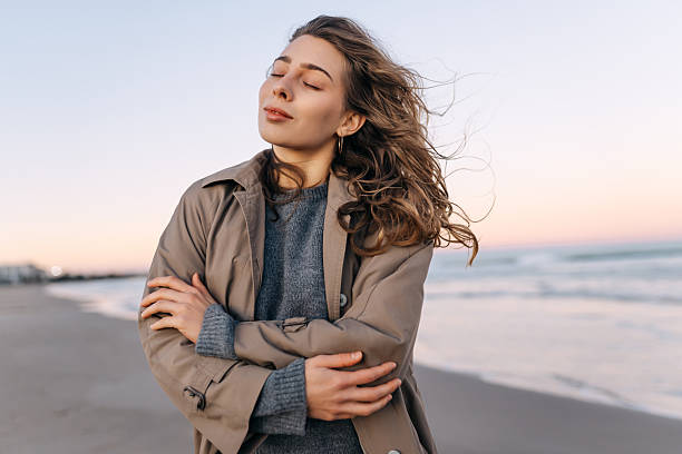 istock Woman stands on beach during sunset with soft breeze and thoughtful expression while enjoying the moment and nature. 2255429492