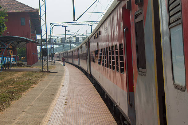 istock Red passenger train standing at an Indian railway station platform with barred windows and empty platform perspective. 2255430616