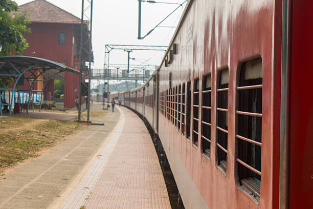 istock Red passenger train standing at an Indian railway station platform with barred windows and empty platform perspective. 2255430646