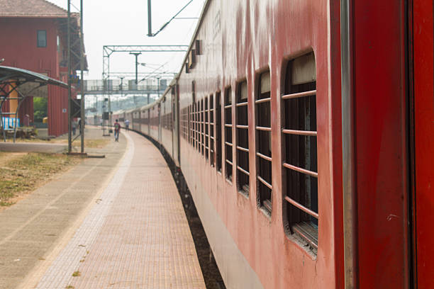 istock Red passenger train standing at an Indian railway station platform with barred windows and empty platform perspective. 2255430647