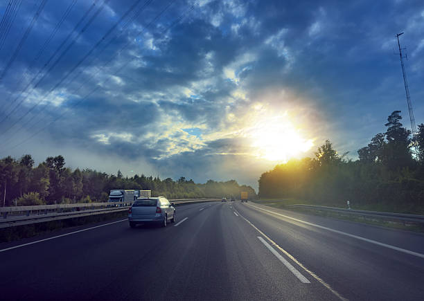 Northern Europe highway traffic at sunset with dramatic clouds, travel and transport sustainability concept