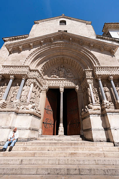 Arles, Provence, France - June 17, 2024: An elderly man sits on the stone steps of St. Tromphine church